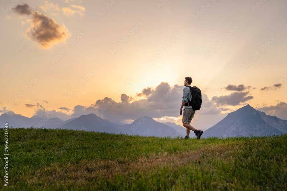 Explorer with backpack hiking in meadow at sunset Explorer with backpack hiking in meadow at sunset