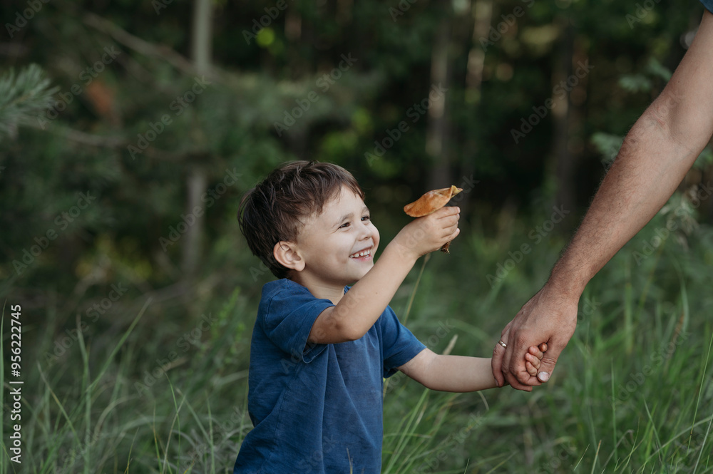 Happy boy with mushroom holding hand of father at forest Happy boy with mushroom holding hand of father at forest