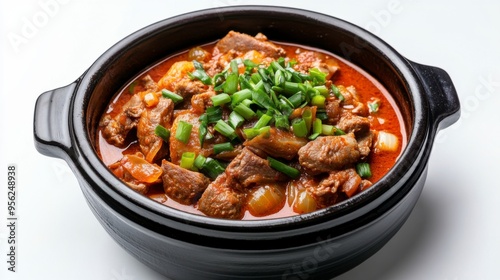 Delicious beef stew in a black ceramic pot, garnished with fresh green onions, perfect for comfort food lovers.