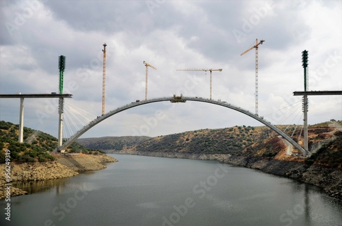 Cranes working on the construction of a large bridge over the river.