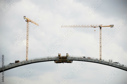 Cranes working on the construction of a large bridge over the river.