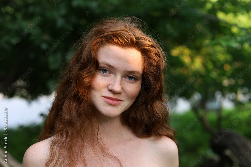 Portrait of smiling girl with long red hair and freckles in park. Young sensual model with naked shoulders, natural female beauty Portrait of smiling girl with long red hair and freckles in park. Young sensual model with naked shoulders, natural female beauty