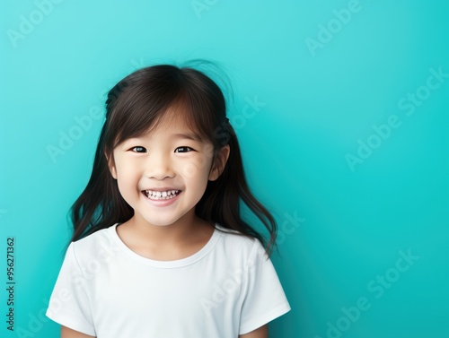 Cyan background Happy Asian child Portrait of young beautiful Smiling child good mood Isolated on backdrop ethnic diversity equality acceptance 