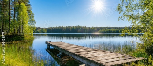 Traditional Finnish and Scandinavian view. Beautiful lake on a summer day and an old rustic wooden dock or pier in Finland. Sun shining on forest and woods in blue sky