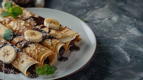 Crepes with chocolate and banana rolled on white plate Thin pancakes blini Sweet dessert Top view with copy space photo