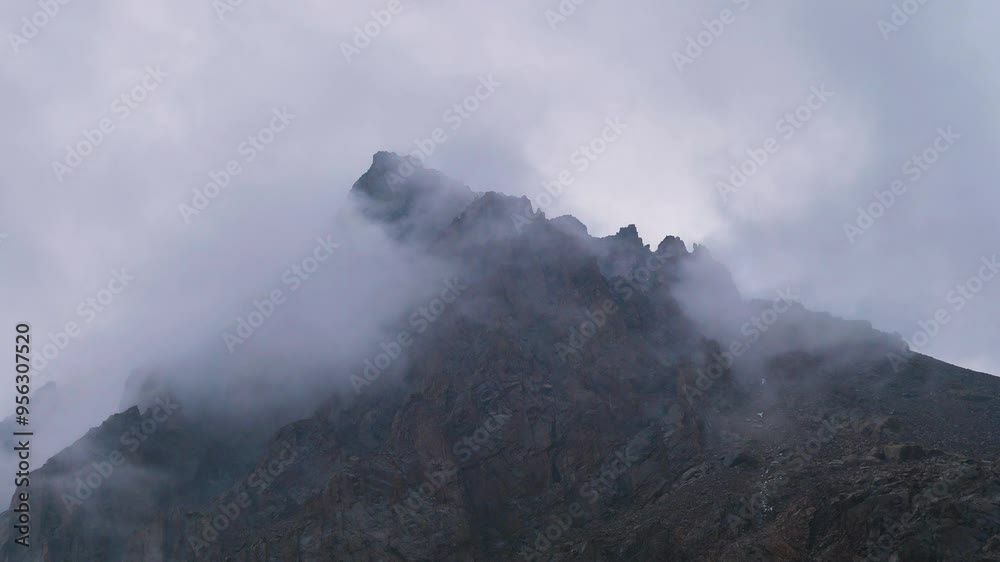 Foggy weather on the Talgar Pass in summer. Tien-Shan mountains in Kazakhstan. Bare rocks high in the mountains in the clouds. Lack of vegetation Foggy weather on the Talgar Pass in summer. Tien-Shan mountains in Kazakhstan. Bare rocks high in the mountains in the clouds. Lack of vegetation
