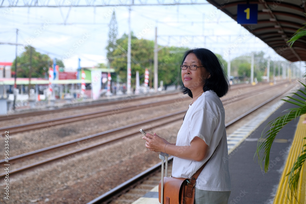 Woman standing on a railway platform, waiting for her train to arrive Woman standing on a railway platform, waiting for her train to arrive