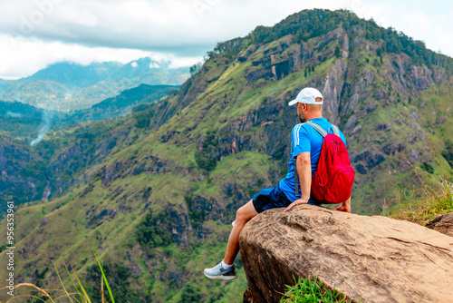 middle-aged man with a backpack went hiking and admires picturesque and epic View from the Small Adam Peak Mountain in Sri Lanka