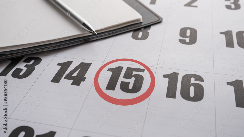 A notebook on a calendar with the 15 th. of the month marked with a red circle A notebook on a calendar with the 15 th. of the month marked with a red circle