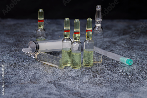 Obraz na płótnie Vaccines, glass ampoules, glass vials containing clear liquid, a syringe, and an insulated hypodermic needle w salonie