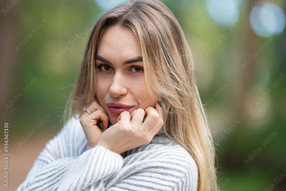 Beautiful blonde woman posing in a park wearing a white sweater Beautiful blonde woman posing in a park wearing a white sweater