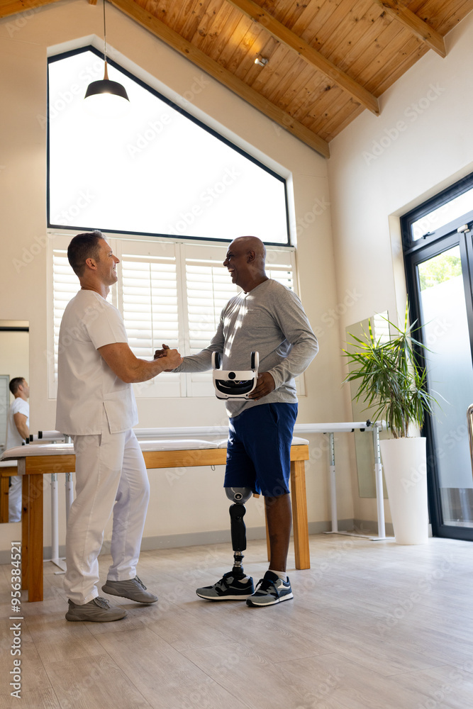 Man with prosthetic leg shaking hands with therapist in rehabilitation center, copy space Man with prosthetic leg shaking hands with therapist in rehabilitation center, copy space