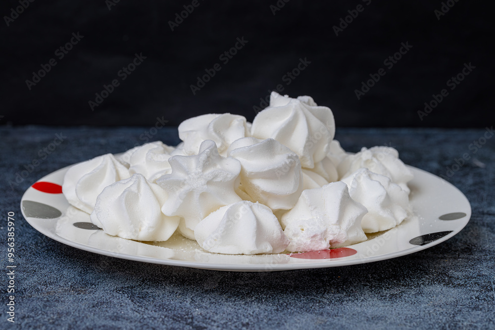 Porcelain plate full of fluffy white meringue. Indoors close-up.