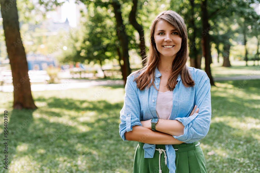 Portrait of smiling woman wearing stylish clothes looking at camera standing in park