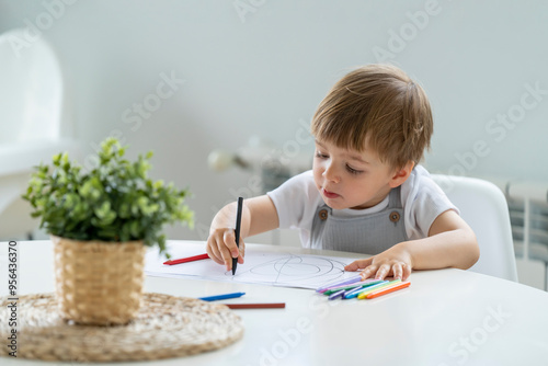 Little Boy Holding Two Crayons with a Pensive Look, Surrounded by Drawing Materials