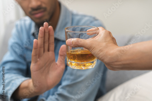 Alcoholism, depressed asian young man refuse, push out alcoholic beverage glass, drink whiskey, sitting alone at night. Treatment of alcohol addiction, having suffer abuse problem alcoholism concept.