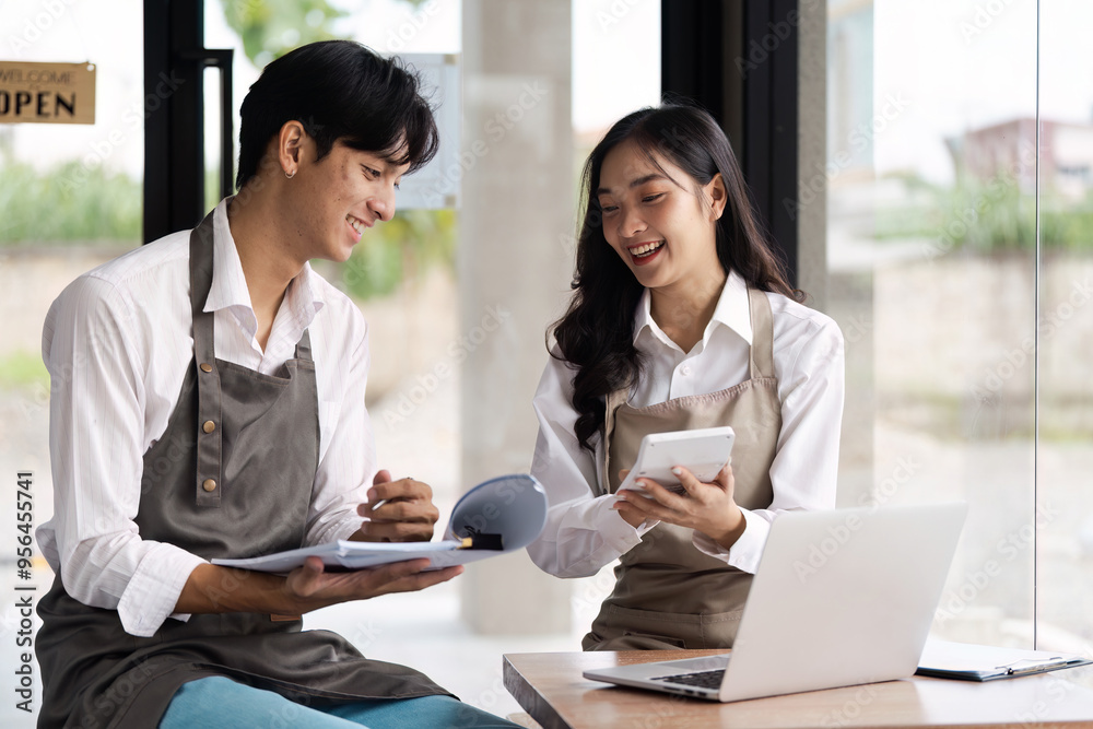 Young Entrepreneur Discussing Business Plans in a Modern Cafe Setting with Laptop and Notebooks Young Entrepreneur Discussing Business Plans in a Modern Cafe Setting with Laptop and Notebooks