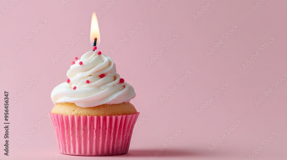 single cupcake with a burning candle on pink background 