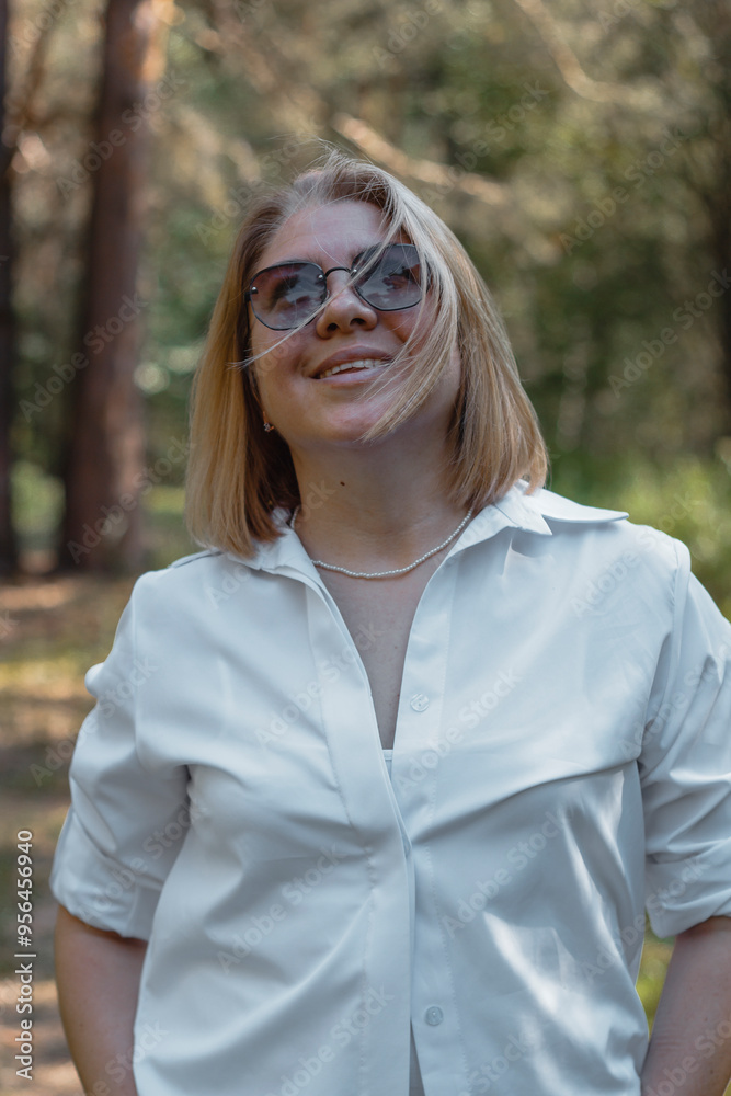 A cute girl in a white shirt and sunglasses walks through the forest, and the wind blows her short hair A cute girl in a white shirt and sunglasses walks through the forest, and the wind blows her short hair