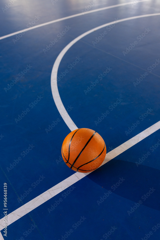 Fototapeta premium Basketball on court, resting on blue floor with white lines, copy space