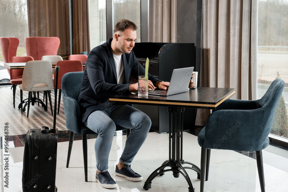 Young businessman working on laptop in modern cafe in hotel Young businessman working on laptop in modern cafe in hotel