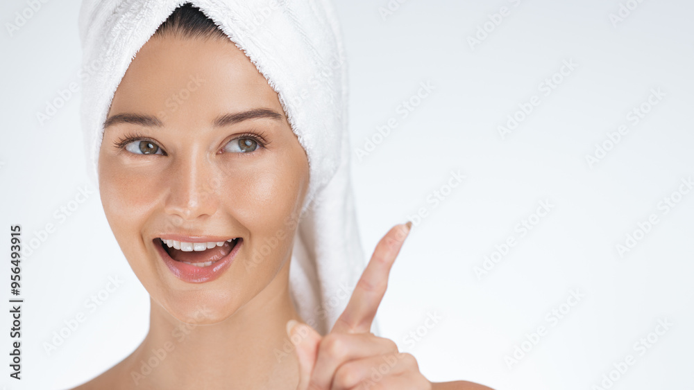 Smiling Woman with Towel on Head Pointing Up in Playful Skincare Moment Smiling Woman with Towel on Head Pointing Up in Playful Skincare Moment