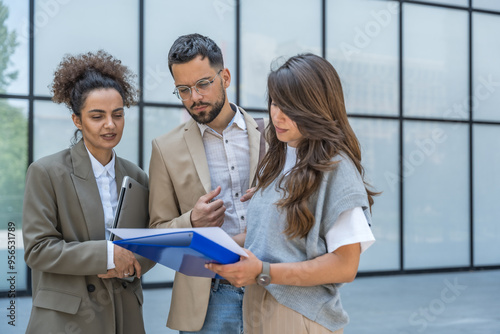 Foto Three diverse business people working and talking focused and thoughtful seriously outside office building, male and female, discussing plans and work project