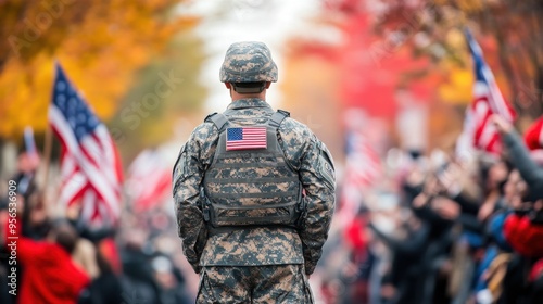 American soldier in camouflage at outdoor military parade with blurred flags and cheering crowd