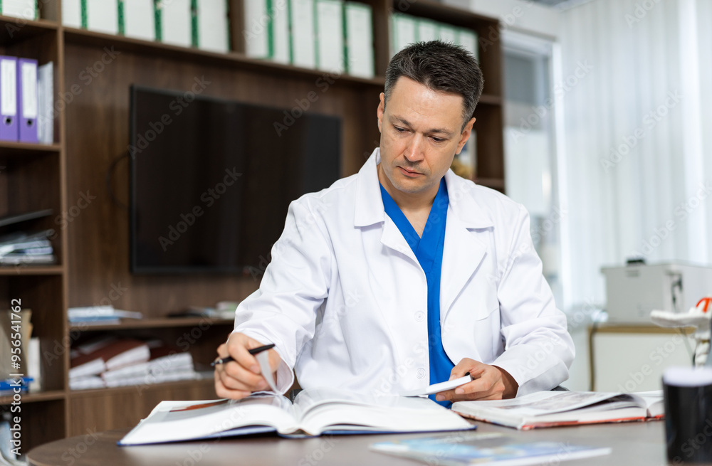 Doctor reviewing patient records in a modern office setting. A healthcare professional is focused on reviewing patient records at his desk Doctor reviewing patient records in a modern office setting. A healthcare professional is focused on reviewing patient records at his desk
