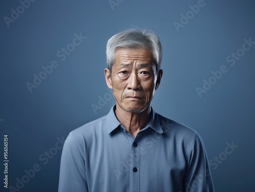 Indigo background sad Asian man. Portrait of older mid-aged person beautiful bad mood expression boy Isolated on Background depression anxiety fear 