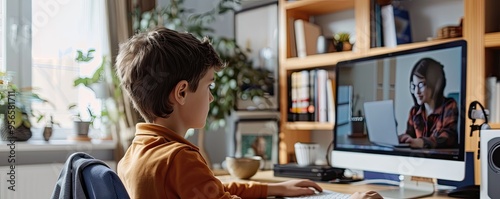 young boy participates in an online school session, attentively looking at the computer screen