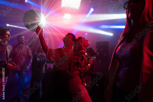 Tableau sur toile Blurry image of a crowd of people dancing under confetti in a disco club
