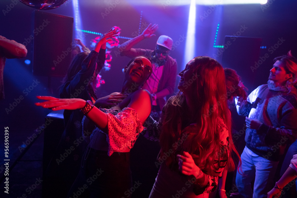 Fototapeta premium Young people enjoying evening at disco. Men and women dancing at club. Nightlife
