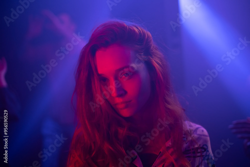 An attractive brunette girl dancing under colorful purple neon light. Club atmosphere