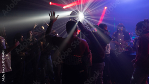 A group of joyful men and women dancing at a nightclub in glowing strobe lights