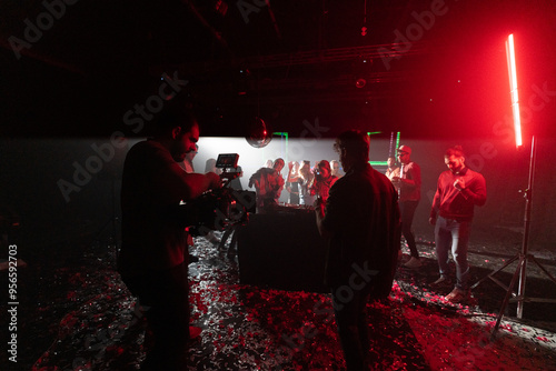 Behind the scene of a dance shooting in nightclub. Cameraman recording live performance with professional camera photo