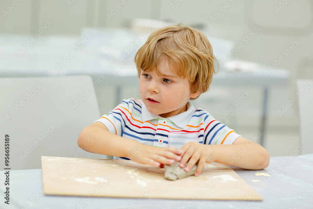 Little blond boy modeling with clay at master class art in a museum, indoors. Creative leisure for kids in kindergarden and at home, indoors.