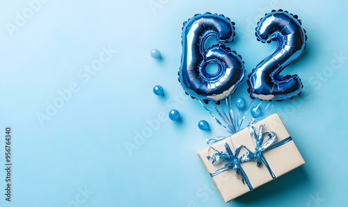 Happy birthday 62th with blue foil balloons and gift box on color background photo