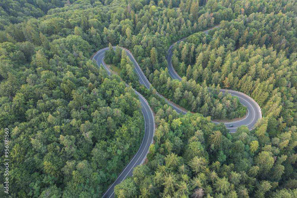 Aerial view of scenic winding mountain road cutting through the green forest Aerial view of scenic winding mountain road cutting through the green forest