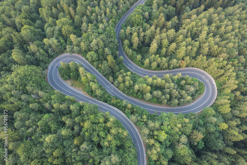 Aerial view of scenic winding mountain road cutting through the green forest