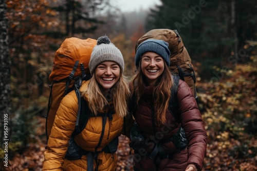 Two friends are hiking through a brightly colored autumn forest, each carrying large backpacks and wearing warm jackets, highlighting the beauty of the season and outdoor adventure. photo