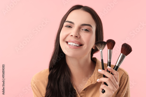 Beautiful makeup. Smiling woman with brushes on pink background