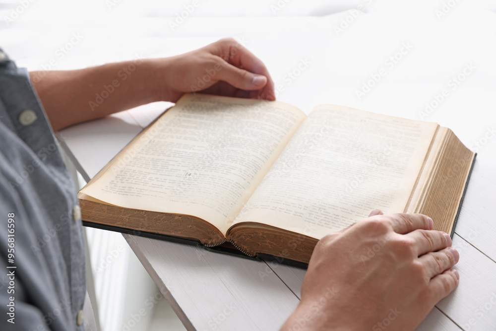 Fototapeta premium Man with Bible at white wooden table, closeup