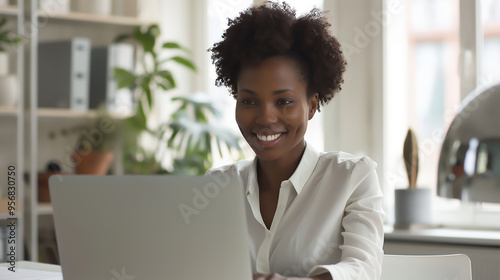 a smiling businesswoman working on a laptop in a clean, minimalistic office, soft lighting