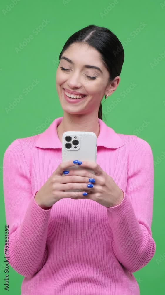 Smiley woman using smartphone for messaging in internet and laughing on green background. Concept of an online entertainment. Vertical video. Smiley woman using smartphone for messaging in internet and laughing on green background. Concept of an online entertainment. Vertical video.