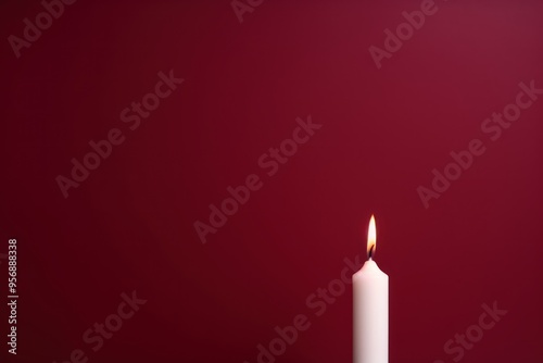 Maroon background with white thin wax candle with a small lit flame for funeral grief death dead sad emotion with copy space texture for display 