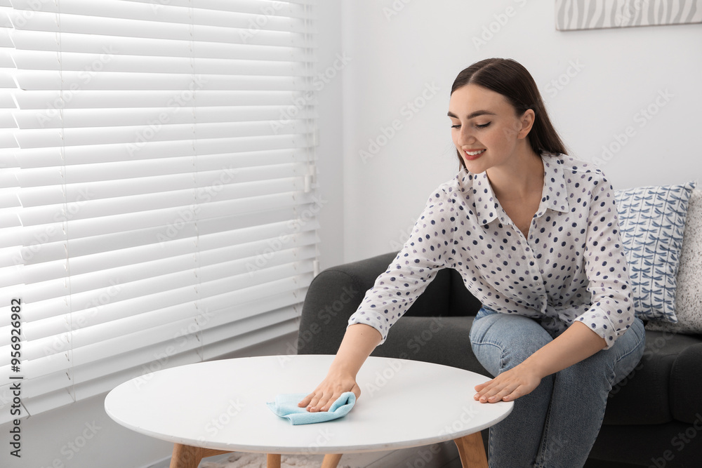 Beautiful young woman wiping coffee table with rag at home Beautiful young woman wiping coffee table with rag at home
