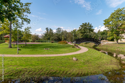 Scenic park with a curved path, a bridge, and green landscaping on a sunny day