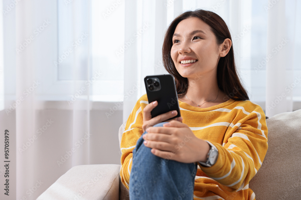 Smiling woman with smartphone at home. Space for text Smiling woman with smartphone at home. Space for text