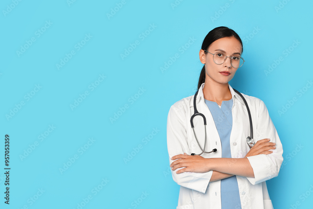 Beautiful nurse with crossed arms on light blue background. Space for text Beautiful nurse with crossed arms on light blue background. Space for text